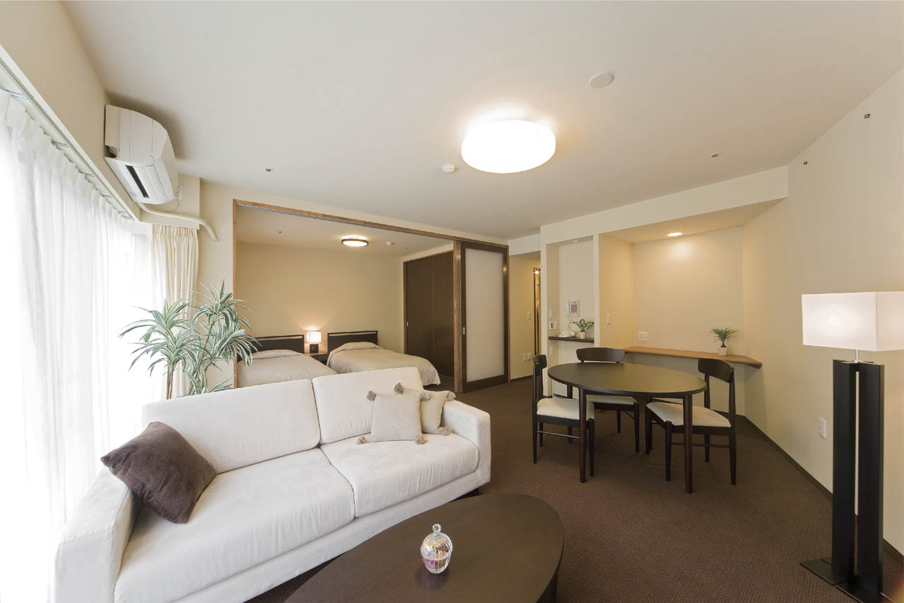 ゆったりとしたフラットフロアの居室。24時間対応の緊急コールや、室内で12時間動きがないとセンサーが察知する生活リズムセンサーなど緊急時にも備えている